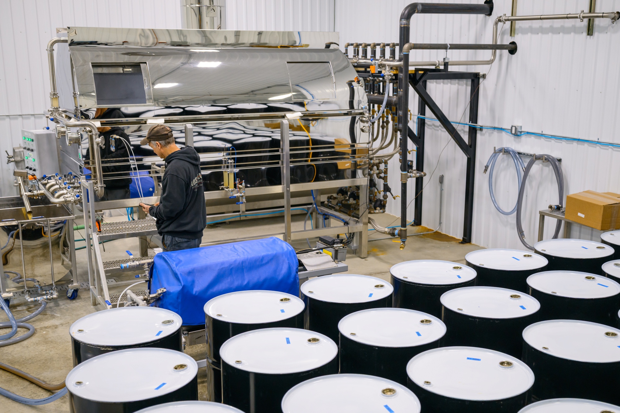 The evaporator and rows of filled syrup barrels in the sugarhouse