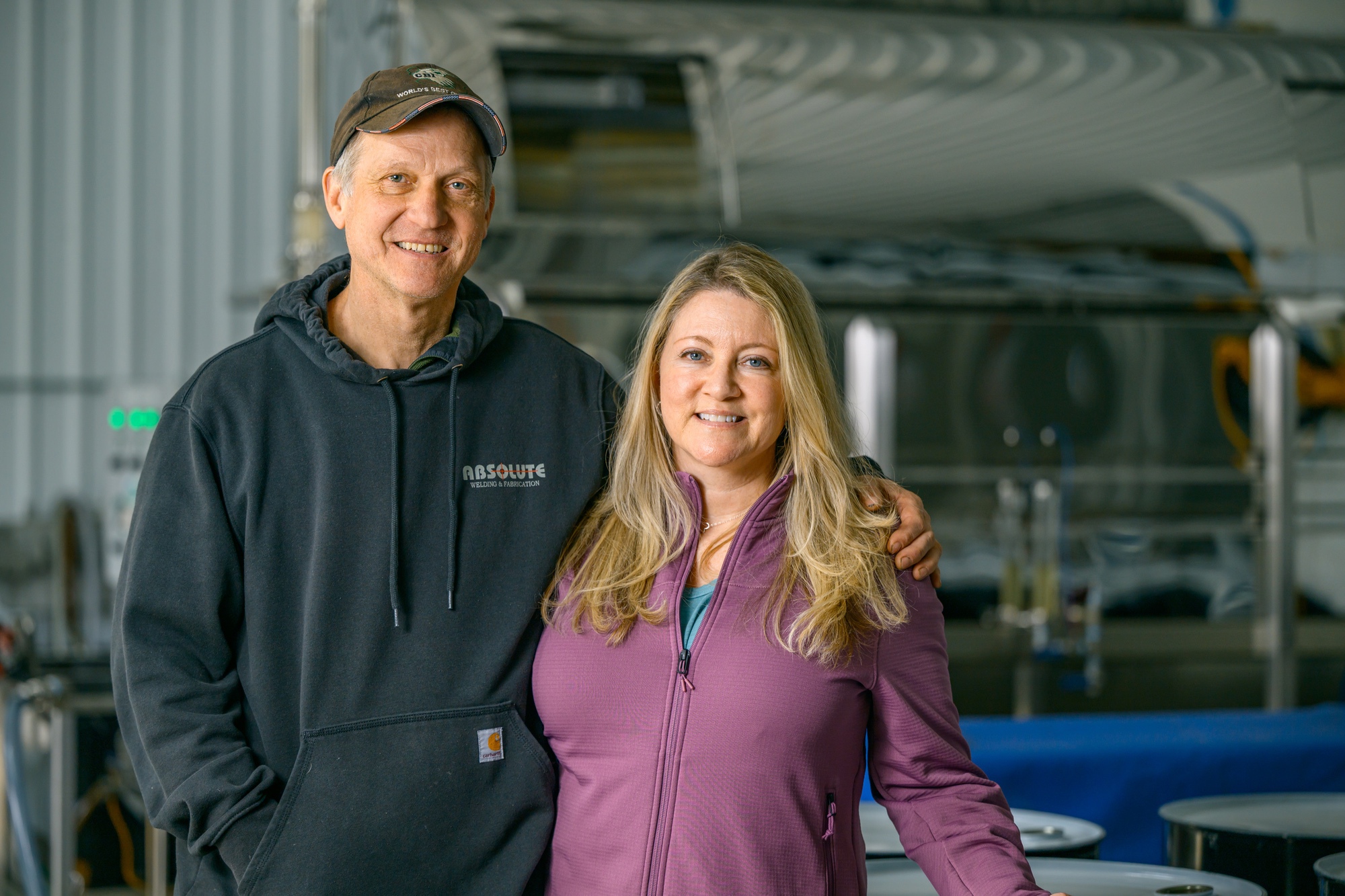 Greg and Lane Bockius standing together in the sugarhouse beside the evaporator